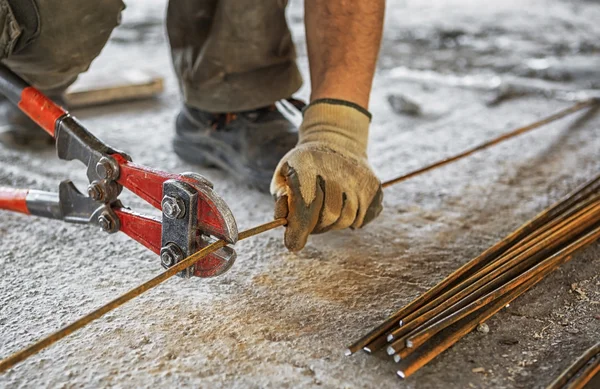 Worker cuts steel bars with bolt cutter — Stock Photo, Image