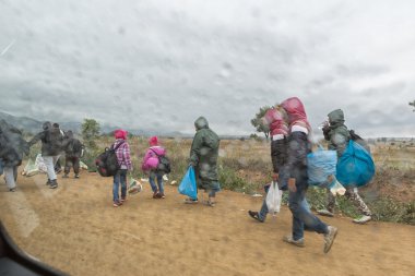 Mültecilerin ve göçmenlerin tozlu yolda yürürken