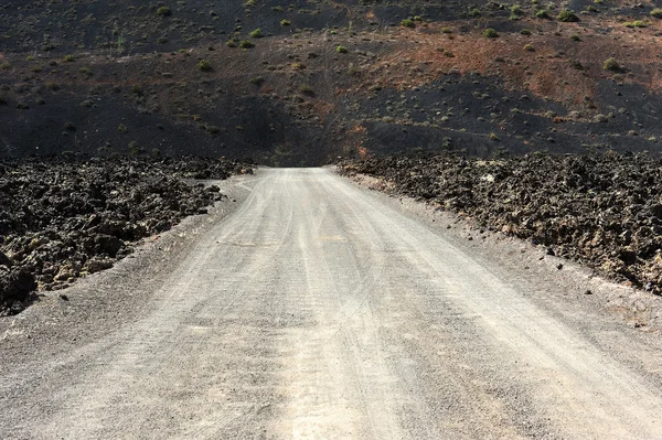 Uma estrada na paisagem vulcânica na Ilha Lanzarote, Ilha Canária — Fotografia de Stock