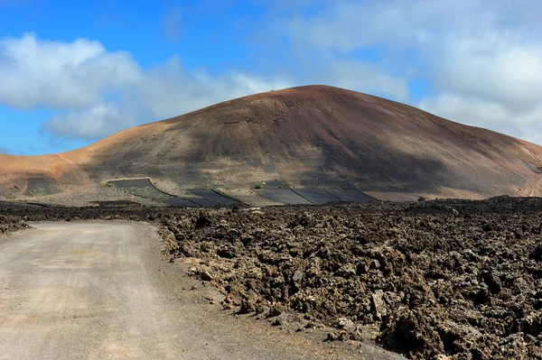 Uma estrada na paisagem vulcânica na Ilha Lanzarote, Ilha Canária — Fotografia de Stock