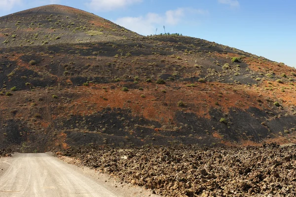 Uma estrada na paisagem vulcânica na Ilha Lanzarote, Ilha Canária — Fotografia de Stock