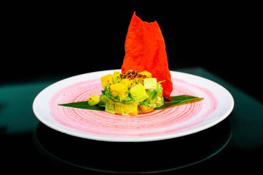 Beyaz tabakta mango, avokado, ton balığı ve susam soslu yakın plan salata.