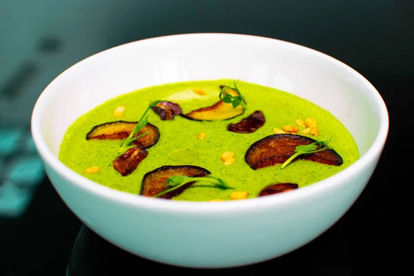cream spinach green soup with dried fruits and peanuts in a deep plate