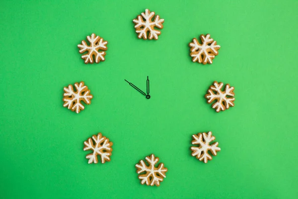 Draufsicht Auf Die Weihnachtsuhr Mit Lebkuchen Schneeflocken Auf Grünem Hintergrund — Stockfoto