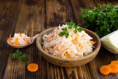 Ahşap arka plandaki kahverengi kasedeki ekşi lahanaya yaklaş.