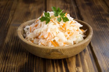 Ahşap arka plandaki kahverengi kasedeki ekşi lahanaya yaklaş.