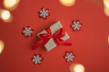 Noel hediyesinin en üst görüntüsü ve kırmızı arka planda kar taneleri