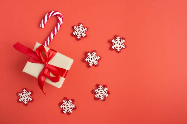 Draufsicht Auf Weihnachtsgeschenk Karamellstab Und Spielzeug Schneeflocken Auf Rotem Hintergrund — Stockfoto