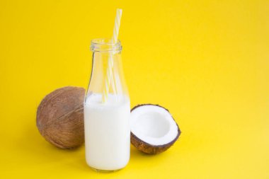 Sarı arkaplandaki cam şişedeki hindistan cevizi sütü ve fotokopi alanı.