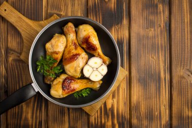 Tahta arka plandaki tavada kızarmış tavuk budu ve fotokopi alanı.