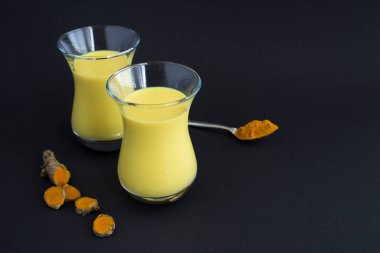 Siyah arkaplandaki gözlüklerde zerdeçal bulunan altın sütün fotokopi alanı ile yakınlaştırılması