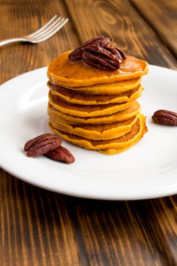 Tahta masadaki beyaz tabakta cevizli ev yapımı balkabağı krepleri.
