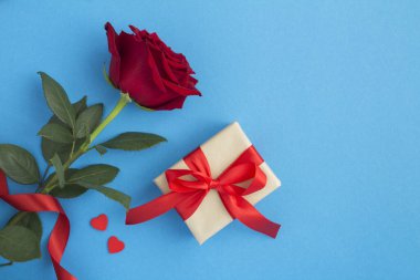 Hediye kutusunun üst görünümü ve mavi arkaplanda kopya alanı olan kırmızı gül