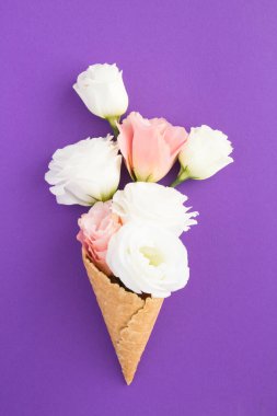 Mor arka planda pembe ve beyaz çiçekli dondurma külahı.
