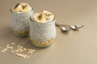 Yulaf ezmeli puding ve gri arka plandaki cam kavanozlarda muz.