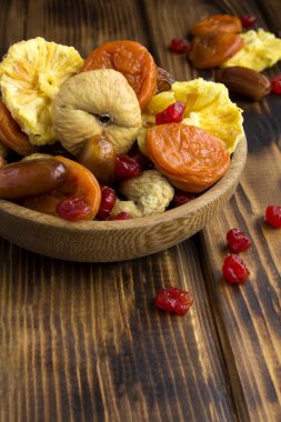 Tahta yüzeydeki kahverengi fiyonkta farklı kurumuş meyveler var. Konum dikey.