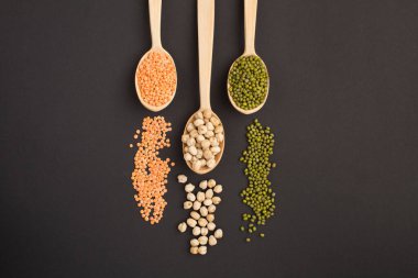 Kırmızı mercimek, nohut ve püre, siyah arka planda tahta kaşıklar.