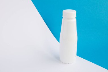 Mavi beyaz arka plandaki beyaz plastik şişeye yaklaş.