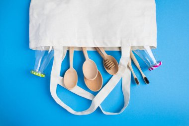 Plastik set Cootton çanta, cam şişeler, tahta kaşıklar ve mavi arka planda bambu diş fırçaları