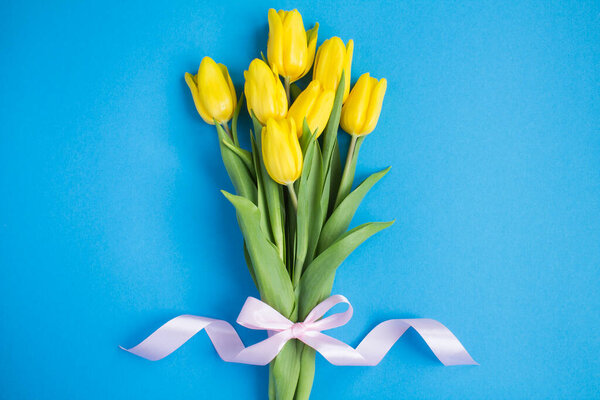 Bouquet of yellow tulips on the blue background