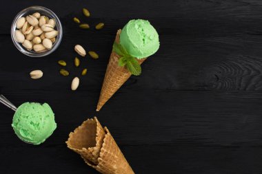 Siyah ahşap arka planda, gözleme külahında fıstıklı dondurma manzarası. Uzayı kopyala Yakın plan..