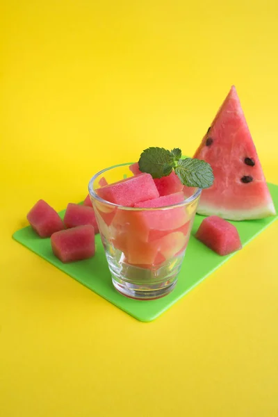 Ijsblokjes Met Watermeloen Het Drinkglas Groene Snijplank Gele Achtergrond — Stockfoto