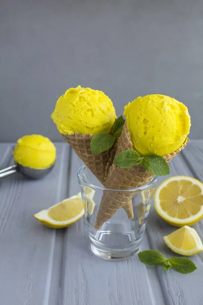 Lemon ice cream in a waffle cone on the gray background. Close-up.