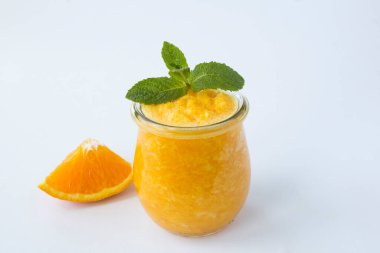 Beyaz arka plandaki cam kavanozda portakallı smoothie veya püre. Yakın plan..