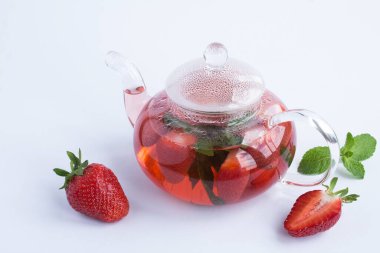 Beyaz arka plandaki cam çaydanlıkta çilek çayı. Sağlıklı bir içki. Yakın plan..