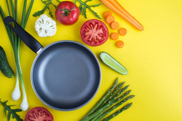 Sarı arka planda boş metal kızartma tavası ve sebze manzarası. Uzayı kopyala Yakın plan..