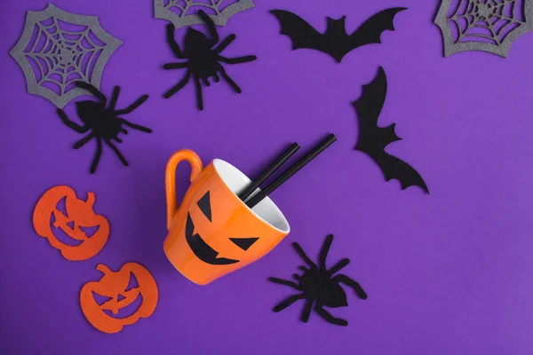 万圣节的作曲 配上橙色杯子 装饰蜘蛛 蜘蛛网和紫色背景的蝙蝠 复制空间 顶部视图 — 图库照片