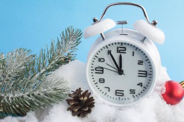 Beyaz çalar saat ve karlı bir arkaplanda Noel kompozisyonu. Yakın plan..