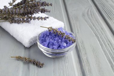 Cam kasede lavanta tuzu ve gri ahşap arka planda beyaz havlu. Yakın plan. Boşluğu kopyala.
