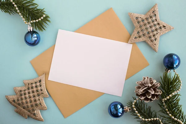 Mavi arka planda yazı, zarf ve Noel kompozisyonu için boş beyaz kağıdın üst görüntüsü. Boşluğu kopyala.