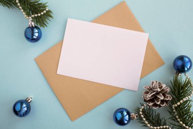 Mavi arka planda yazı, zarf ve Noel kompozisyonu için boş beyaz kağıdın üst görüntüsü. Boşluğu kopyala.