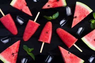Siyah ahşap zemin üzerinde karpuz olan buzlu şekerlerin üst görüntüsü. Yakın plan..