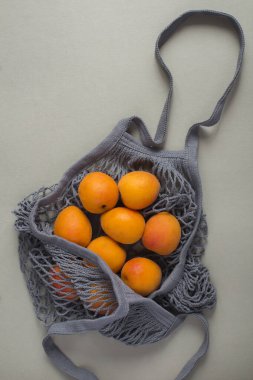 Plastik poşet konsepti yok. Gri arka planda kayısısı olan gri bir çanta. Üst görünüm.