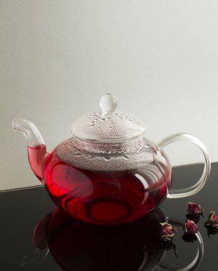 Siyah masadaki cam çaydanlıkta güllü pembe çay. Yakın plan..