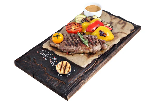 Ribeye steak na pergamenový papír a deska z spáleného dřeva. — Stock fotografie