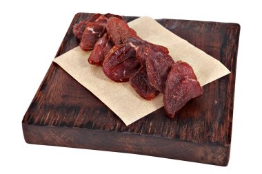 Slices of dried meat on serving dark brown board isolated. clipart