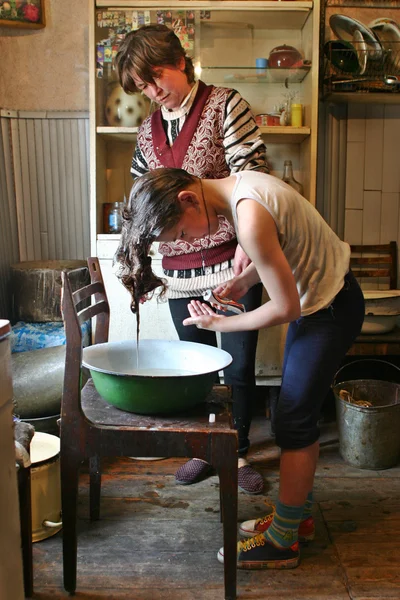 Dziewczyna myje głowę w dorzeczu szkliwa, Rosja farmhouse. — Zdjęcie stockowe