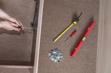 Bed frame assembling, hands carpenter screwed screw using screwdriver. clipart