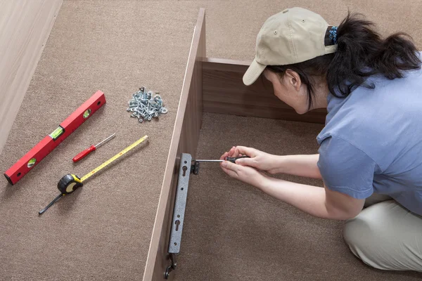 Woman housewife putting together assemble bed frame, using hand tools. — Stock Image Woman housewife putting together assemble bed frame, using hand tools. Stock Picture