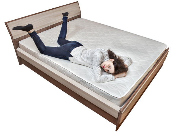One young Caucasian woman relaxing on spring mattress wooden bed. 