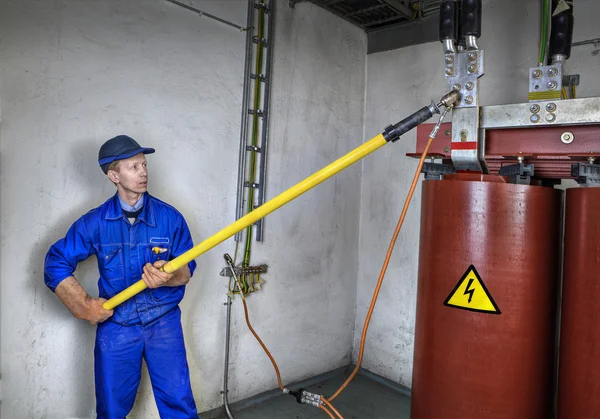 Electrician engineer uses insulating rod to earth grounding transformer. — Stock Photo, Image