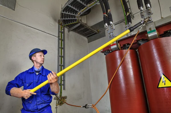 Worker uses insulating stick to earth grounding transformer. — Stock Photo, Image