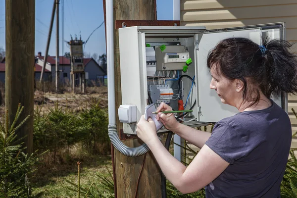 屋外電気メーターの測定値に農村成人女性 — ストック写真