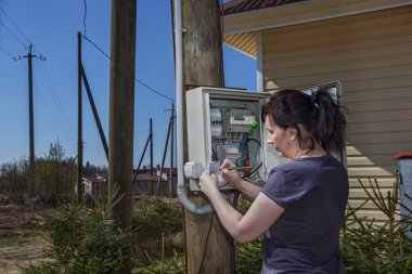 Woman takes readings of the electric meter, outdoors. clipart