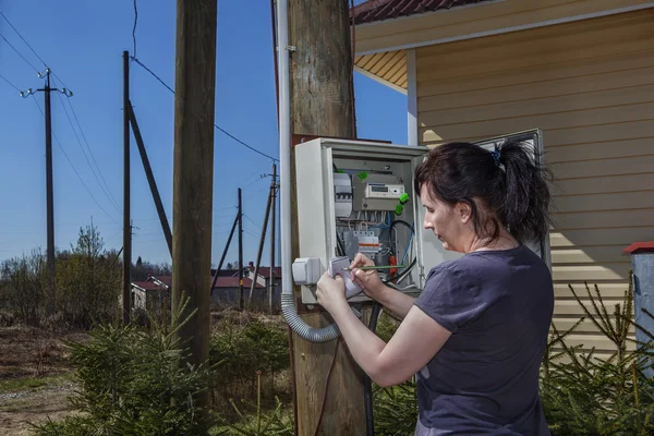 Woman takes readings of the electric meter, outdoors. — Stock Photo, Image