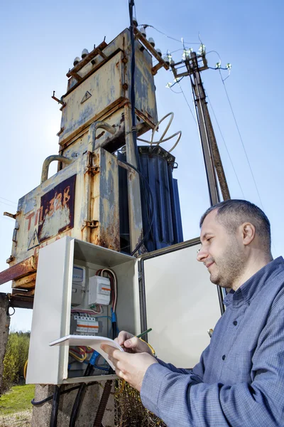 Técnico aldeano escribiendo lectura de contador de electricidad en portapapeles . — Foto de Stock